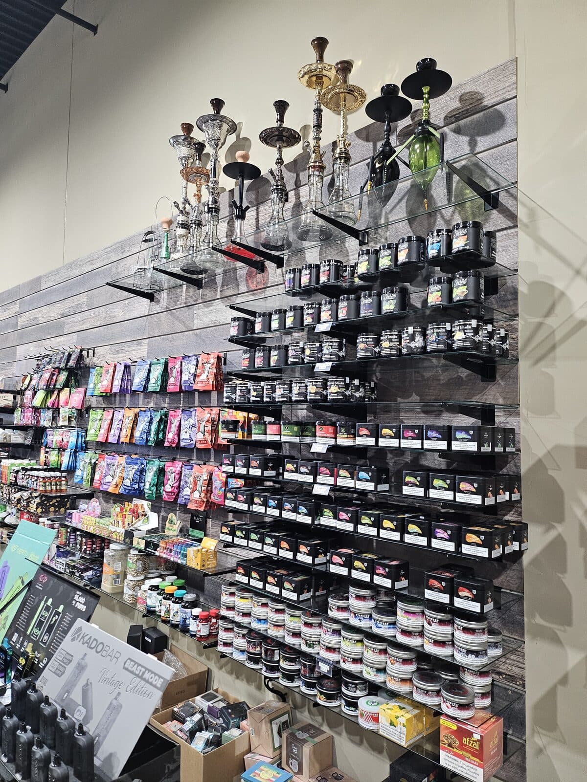 Hookah wall and shisha selection above the accessory shelves at 3 Heads Smoke Shop in Elgin
